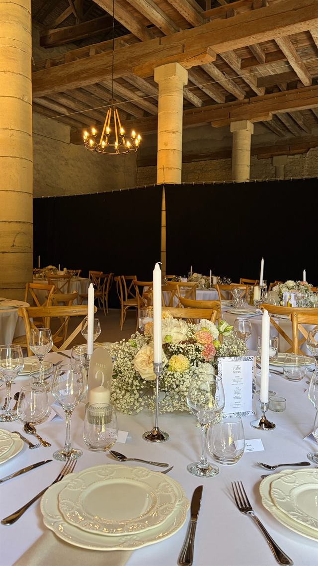 Longue tablée sous charpente, bougies et lustre — Château de Pange